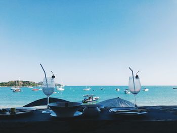 Boats moored in sea against clear blue sky