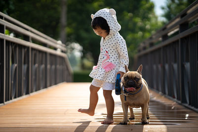 Full length of girl walking with dog on footbridge