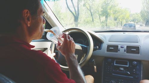 Man sipping drink while driving car