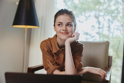 Portrait of young woman using laptop at home