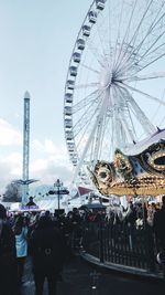 People in amusement park ride against sky