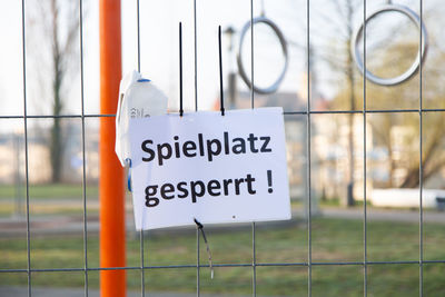 Close-up of information sign hanging on fence