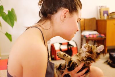 Close-up of young woman with cat sitting at home