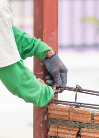 Midsection of man holding umbrella standing against railing