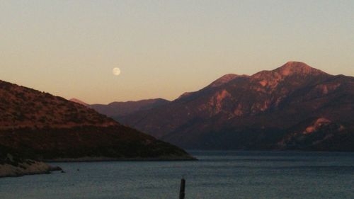 Scenic view of sea and mountains against sky during sunset