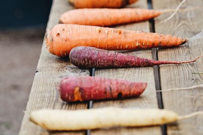 High angle view of different colored carrots lined up in a row on a rustic wooden table table