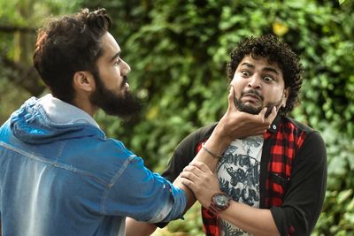 Two people fighting while standing outdoors against trees