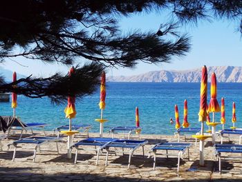 Chairs on beach against blue sky