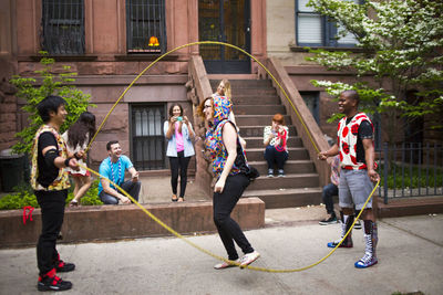 Friends enjoying while performing double dutch on sidewalk