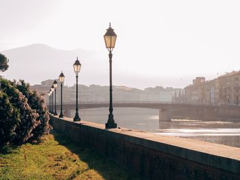 Street light by river in city against clear sky