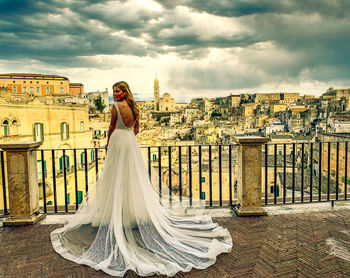 Woman standing with umbrella against sky in city