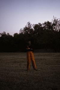 Blurred motion of person walking on field against clear sky