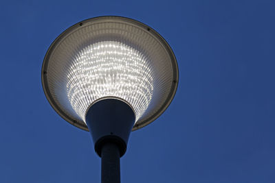 Low angle view of illuminated street light against blue sky