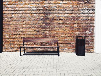 Empty bench against brick wall