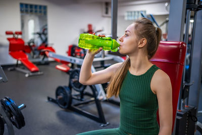 Side view of woman lifting dumbbell in gym