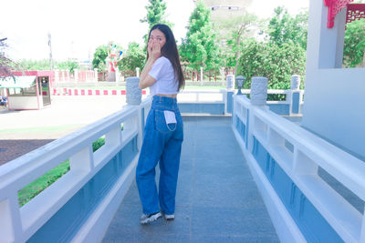 Portrait of young woman standing against railing