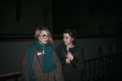 Friends standing against wall at night