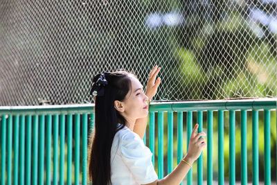 Portrait of woman standing against fence