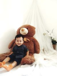 Portrait of cute baby girl sitting on bed