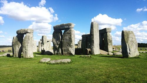Buildings on field against cloudy sky