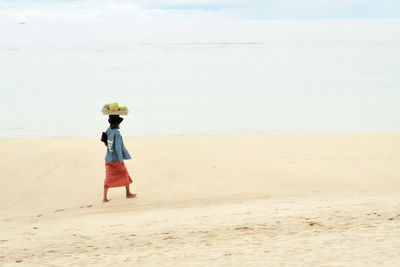 Woman standing on beach against sky