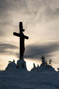 Cross on snow against sky during sunset