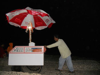 Rear view of man and woman standing on table at night