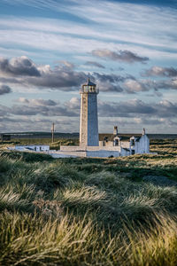 Lighthouse by sea against sky