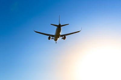 Low angle view of airplane flying against clear blue sky