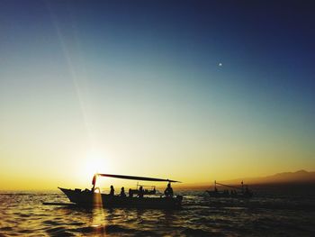 Silhouette people on boat in sea against sky during sunset