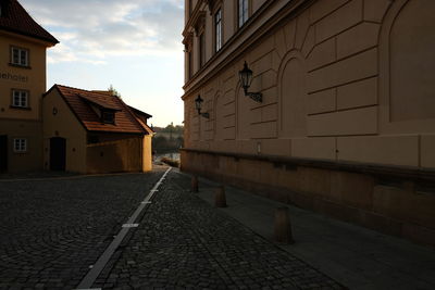 Street amidst buildings against sky during sunset