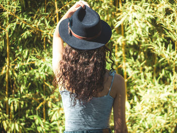 Young girl on her back with a hat on her head against bamboo leaves