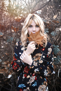 Portrait of young woman standing against trees