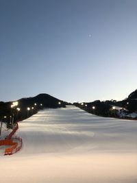 Snow covered illuminated mountains against sky at night