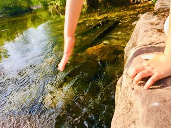 Low section of person standing on rock by stream