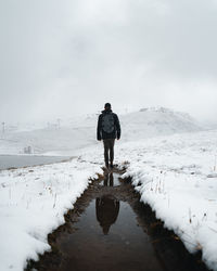 Rear view of man standing on snow covered landscape