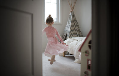 Rear view of girl in ballet costume dancing at home seen through doorway