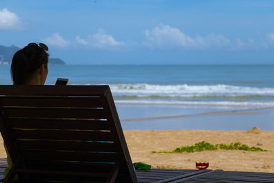 Rear view of woman on beach against sky