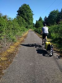 Rear view of man riding bike on road