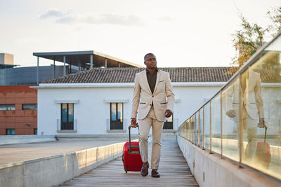 Businessman with a red suitcase walking through a city.