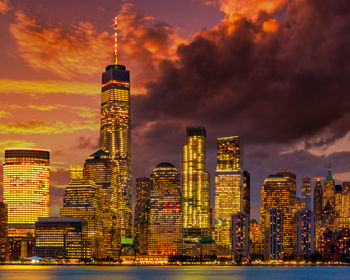 Illuminated buildings against cloudy sky during sunset