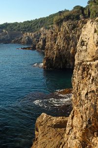 Rock formations by sea against clear sky