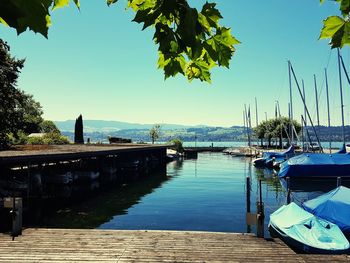 Boats moored on sea against clear blue sky