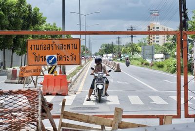 Man with motor scooter on zebra crossing by sign board