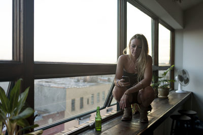 Young woman crouching on a window sill