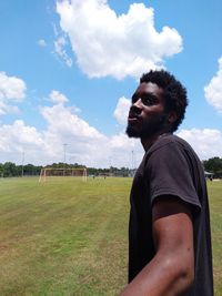 Young man standing on soccer field against sky