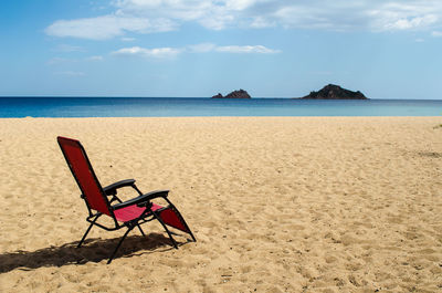 Empty chair at beach against sky