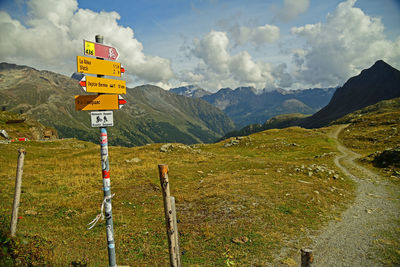 Road sign on landscape against sky