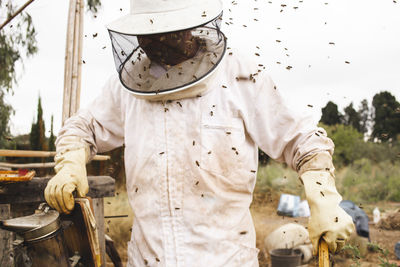 Beekeeper wearing protective workwear working in apiary