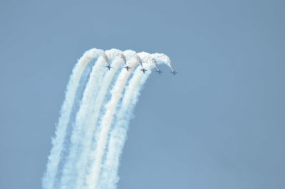 Low angle view of airshow against clear blue sky